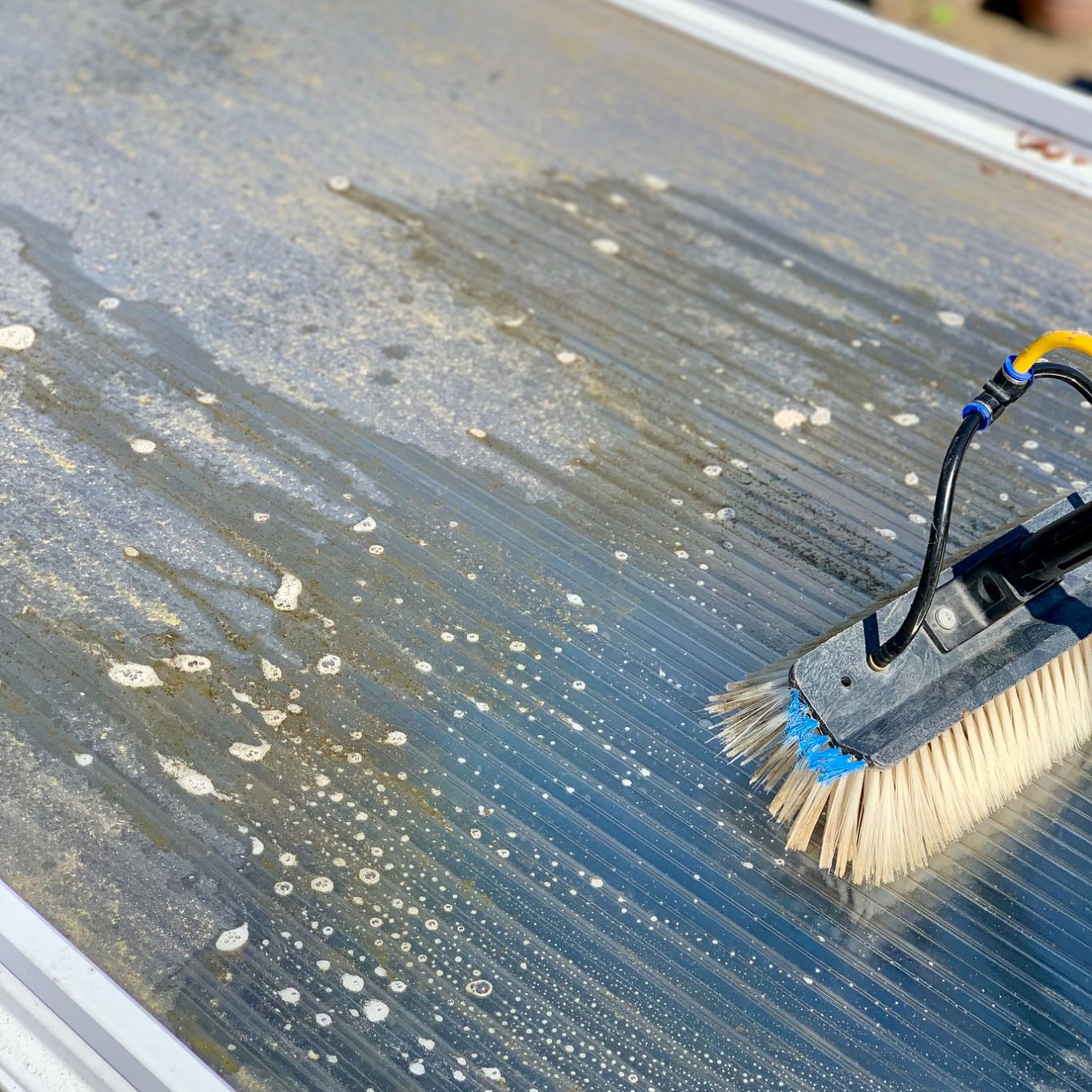 Water fed pole cleaning dirt off a conservatory roof in Englefield green