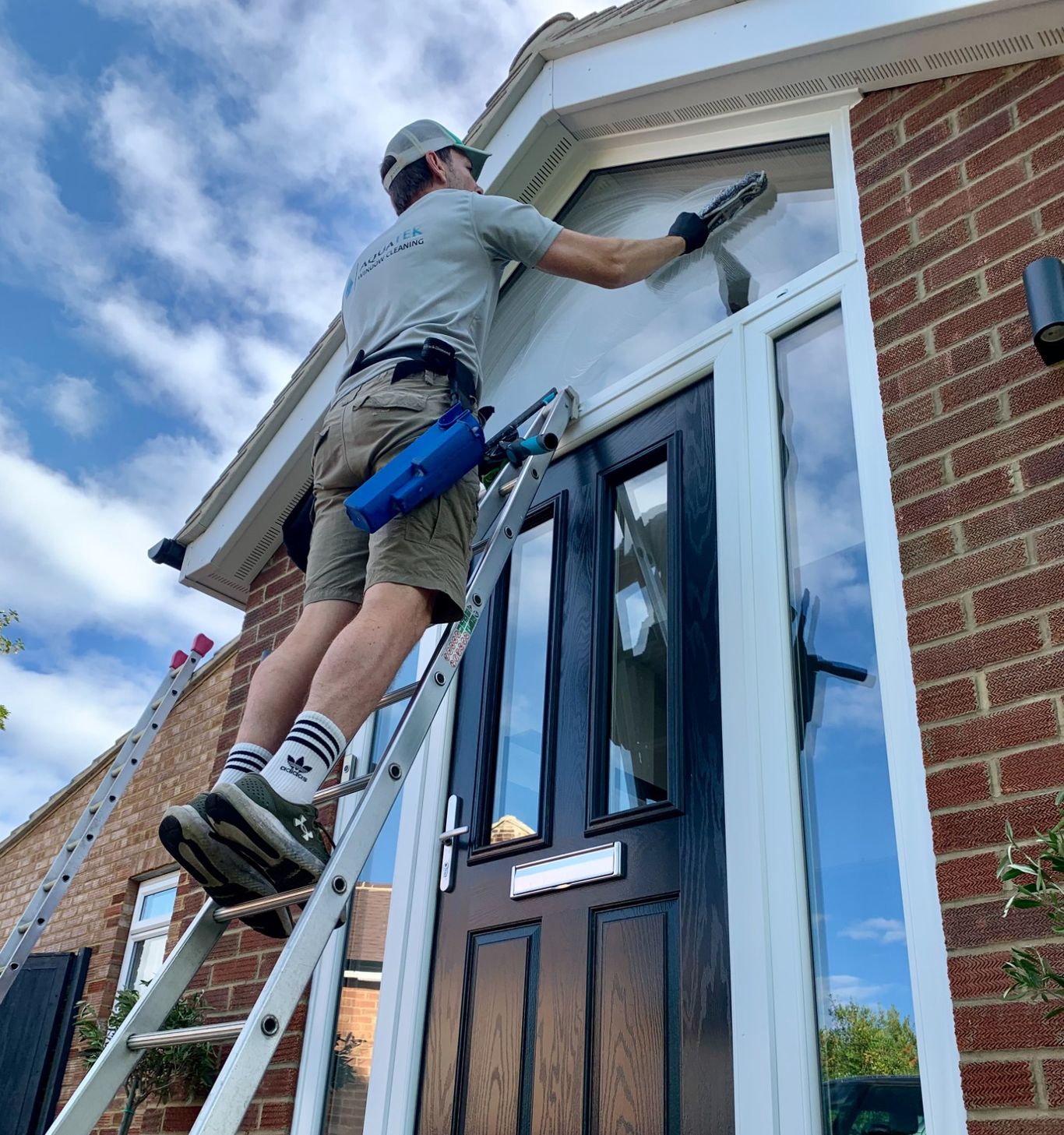 Window cleaner using soap and squeegee to clean large bi-fold door