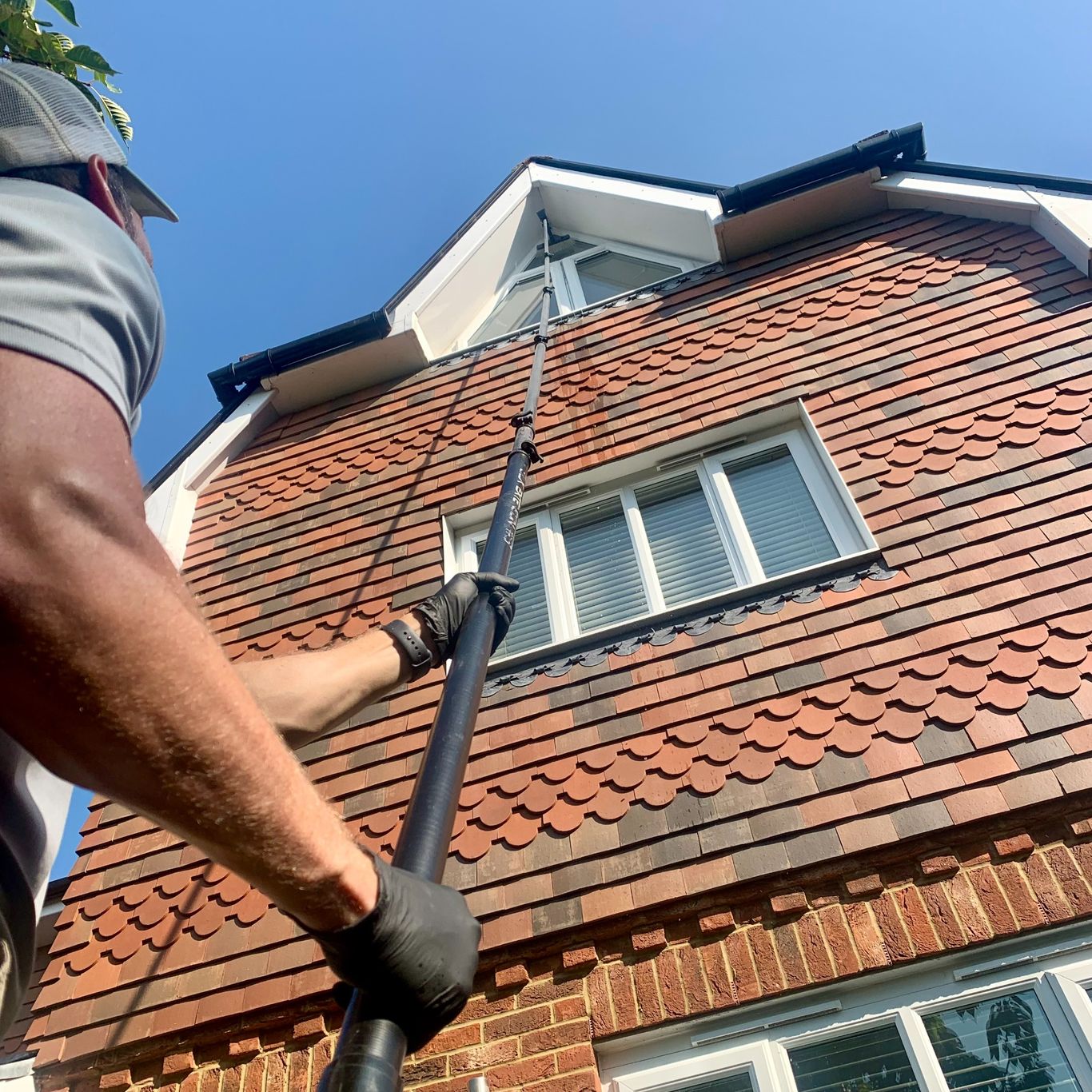 Aquatek window cleaning operative using water-fed pole to reach 3rd story windows